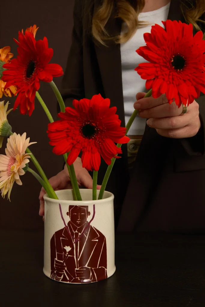 Jarrón de cerámica ilustrado por Justine Franco para Kave utilizado como florero con gerberas rojas.